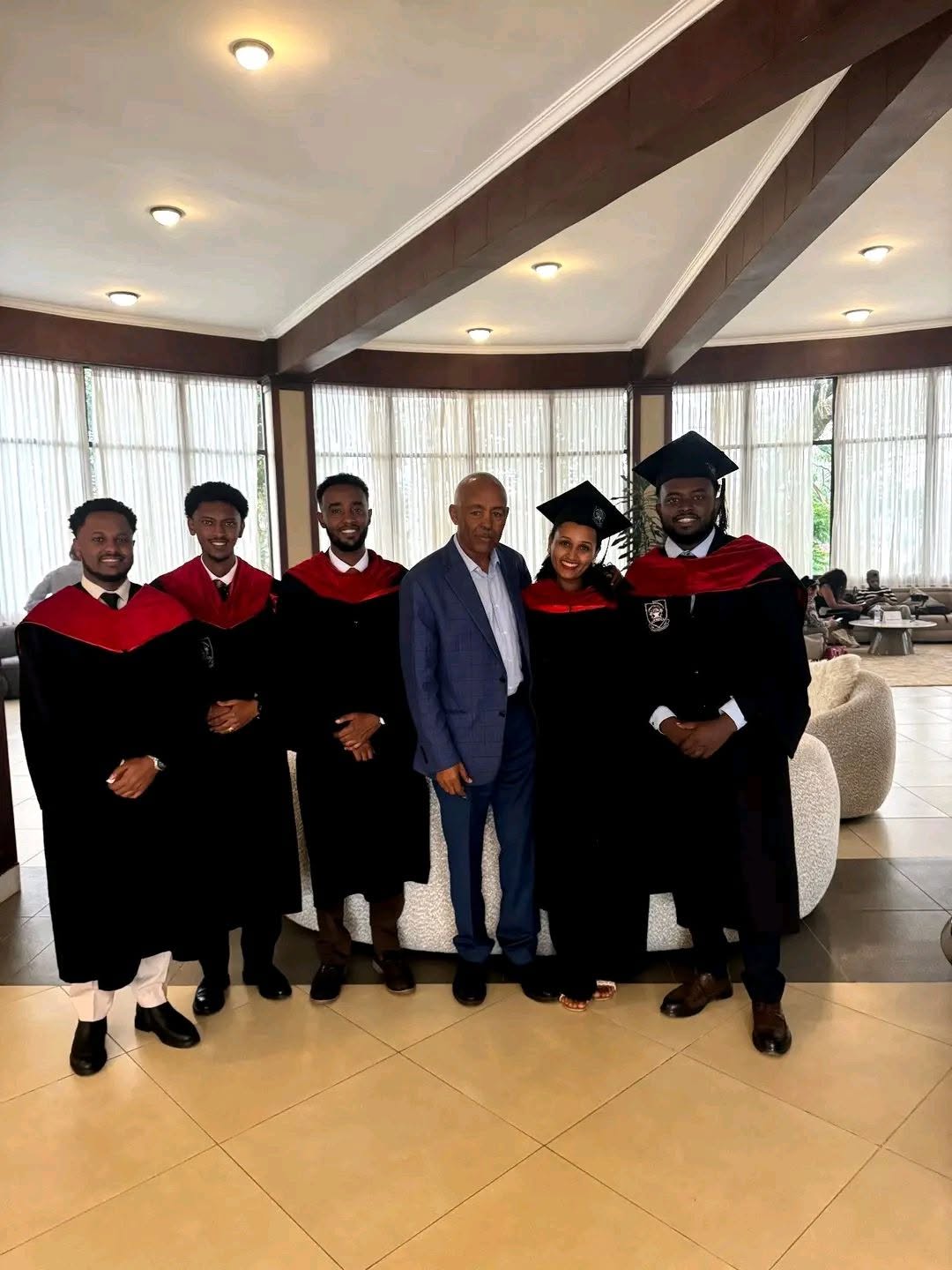 Graduates in academic gowns standing together indoors