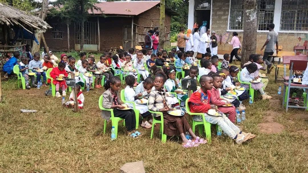 Children and adults gathered outdoors during a community meal