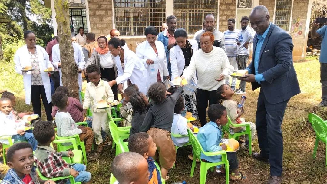 Adults standing with children at the outdoor community gathering