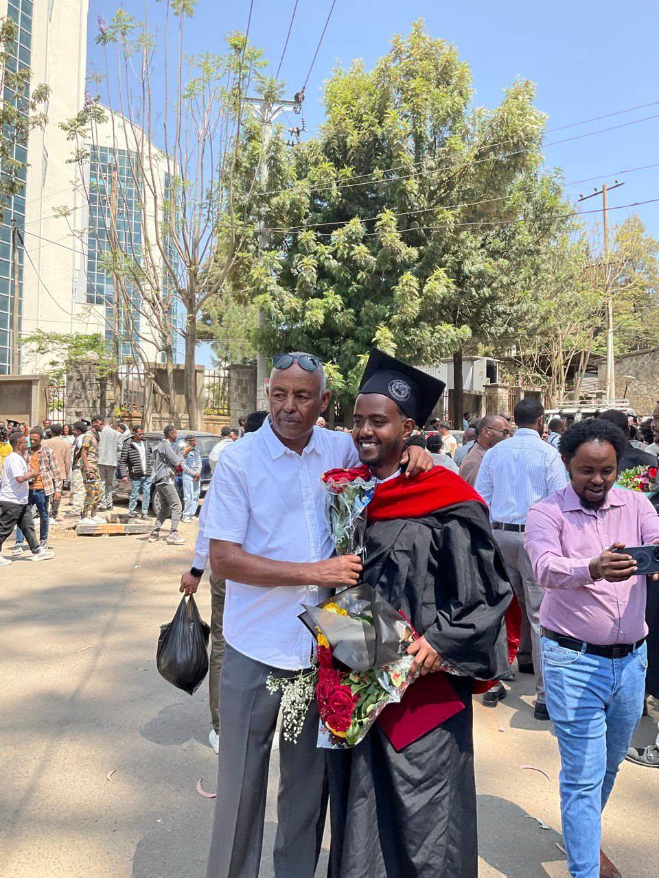 A graduate holding flowers pictured with people at graduation