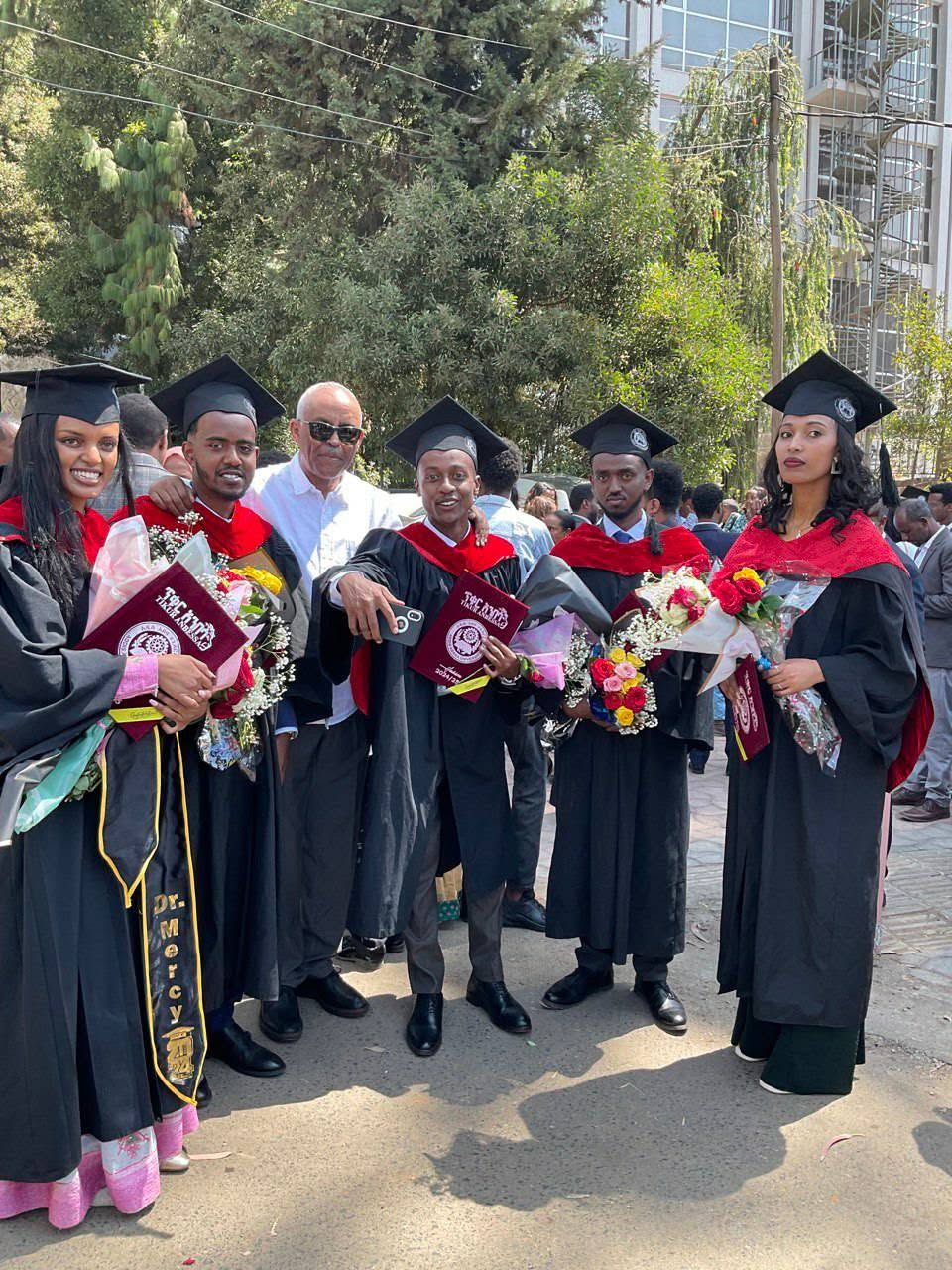 A group of graduates with bouquets at the graduation celebration
